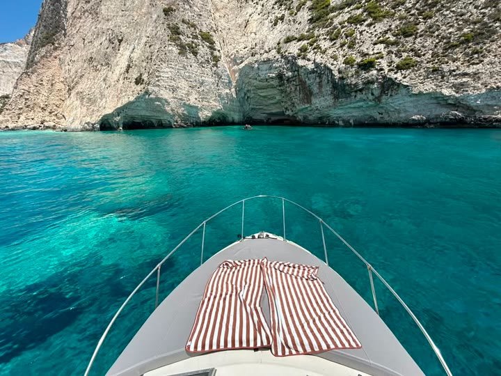 Striped towels laid on the bow sunbeds of the MareWaves boat above a turquoise cove and sea caves