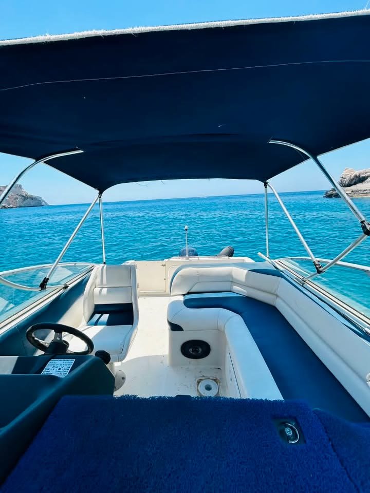 The shaded cockpit of the MareWaves boat, with the helm, white seating and open turquoise sea beyond